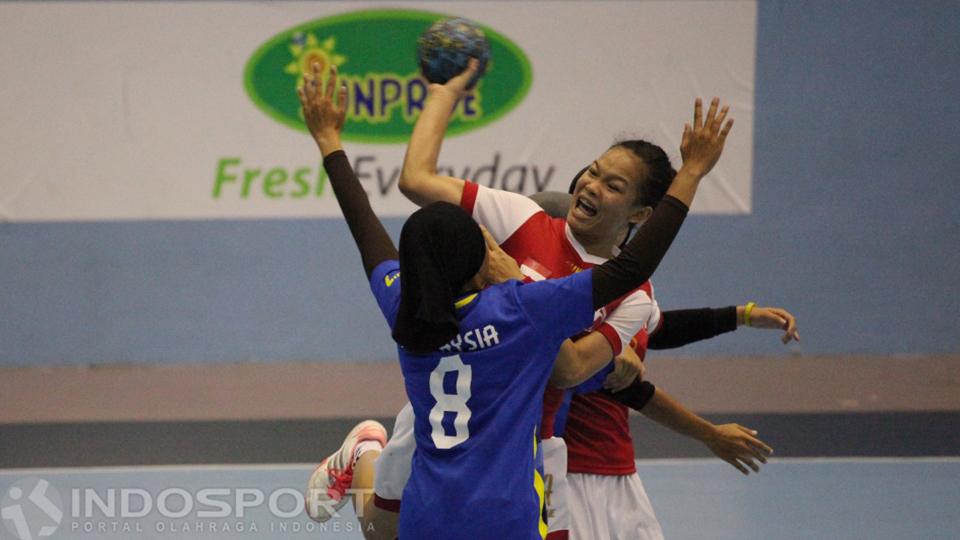 Pemain putri Indonesia (tengah) dihadang lajunya oleh pemain putri Malaysia.